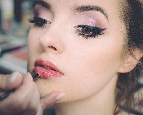 woman getting lips applied with lipstick
